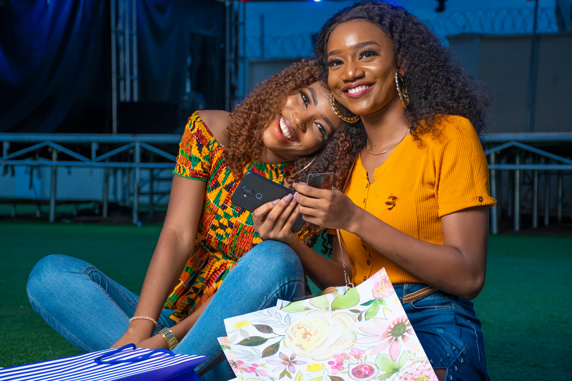 two black ladies sitting at night with shopping bags